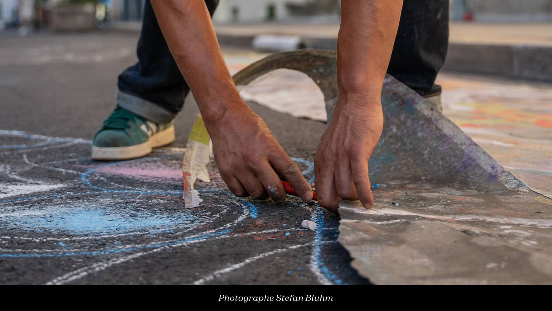 Diego fait une fresque sur le sol à la craie, prise de vue de ses mains qui dessinent